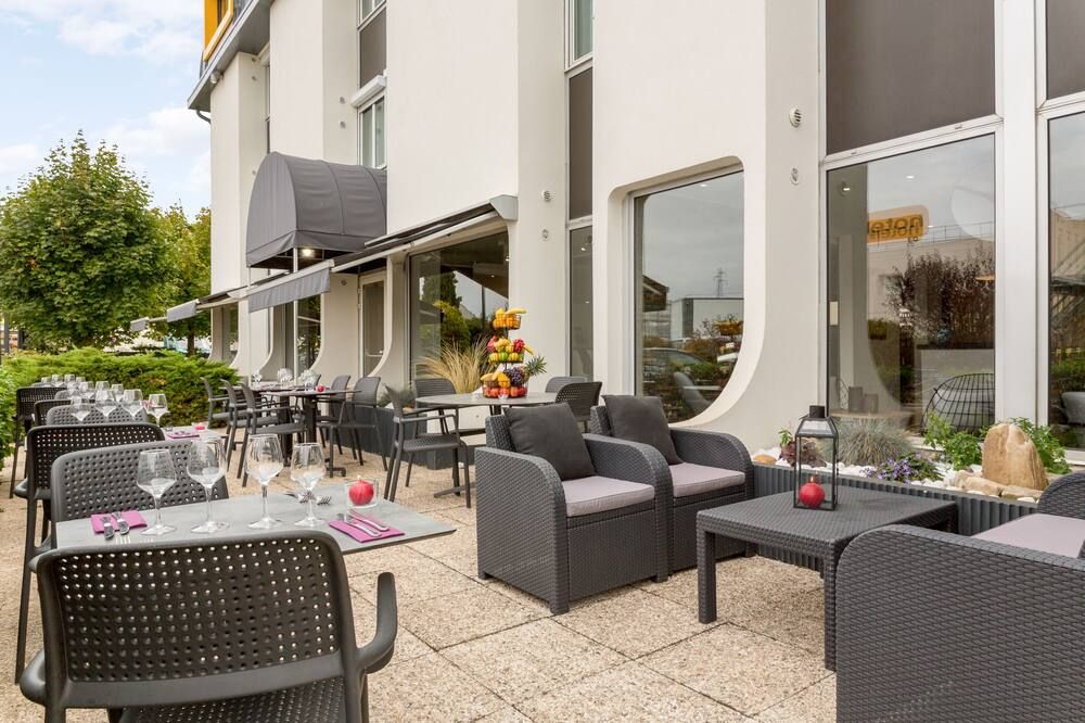 Terrasse de l'hôtel avec tables dressées et salon de jardin